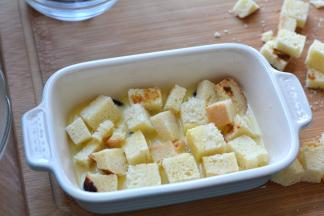 烤碗里先铺一层葡萄干，再铺一层吐司块，倒一部分牛奶鸡蛋液没过吐司块