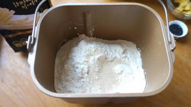 先将液体材料入面包机内桶，再依次倒入白糖、盐、面粉，最后倒入酵母；黑芝麻入料盒中