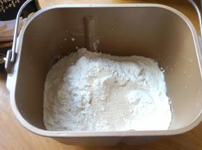 先将液体材料入面包机内桶，再依次倒入白糖、盐、面粉，最后倒入酵母；黑芝麻入料盒中