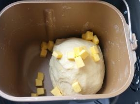 待一个揉面程序结束后，将软化的黄油入桶中，剩下的工作全部交给面包机啦