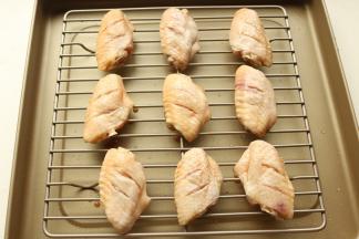 烤盘里加烤架，腌好的鸡翅摆在烤架上。