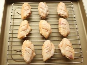 烤盘里加烤架，腌好的鸡翅摆在烤架上。