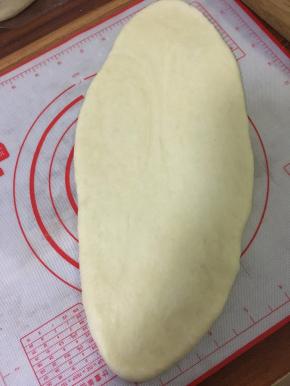取一块面团，压平，用擀面杖从中间往上下两端擀，擀成长舌头状，擀面要轻哟。