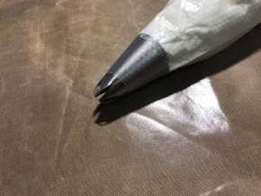 提前准备好的裱花袋套杯子上，罐进去一些动作轻柔，提前准备好也是避免做好的溶豆糊放久了消泡，做完就挤，不给面糊消泡的机会，此时把烤箱预热90度。