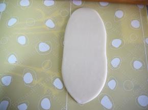 从面团的中间往上下两端轻轻擀开，擀成椭圆形的面片