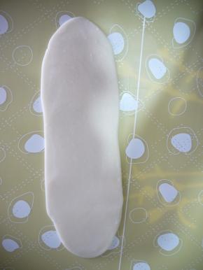 从面团的中间往上下两端轻轻擀开，擀成长条状，由下至上卷起面片