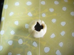 对夹方向朝上，用擀面杖擀成边缘薄，中间厚的圆片，放入一颗豆沙馅，用虎口的位置将饼皮慢慢收拢