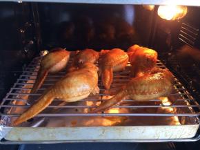 用牙签将收口扎紧，鸡翅包好饭后放在烤网上，底下用烤盘垫锡纸接着烘烤时掉的油