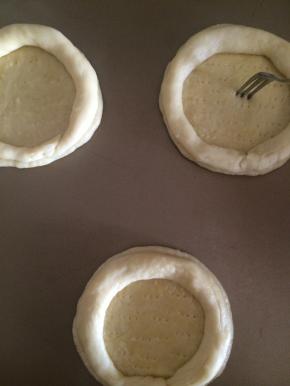 取一个40克的面团擀开成圆形，在圆饼上液一层蛋液，把20克的面团搓成长条围圆饼一圈捏紧收口处，用叉子在底部叉上细孔