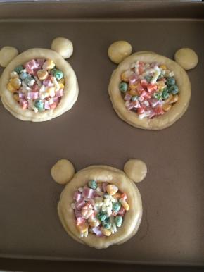 把5克的面团揉圆按扁，贴上当耳朵，四周刷一层蛋液把拌好的蔬菜粒铺在圆饼中间