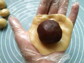 取一个饼皮按扁；包入豆沙馅