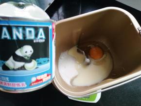 面包桶里加入一个鸡蛋、炼乳、细砂糖和盐对角分开放