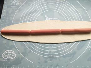 剩下的边角料和1/3面团擀成长长的面片，宽度能包住香肠‘；把香肠排列