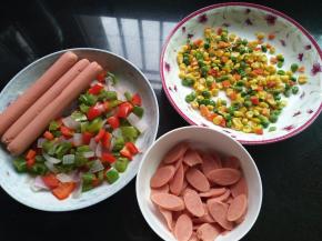 面团发酵期间，来做馅料，把青红椒和玉米粒豆放微波炉烘干，2根香肠切小片（蔬菜类最好是提前烘干或者炒干水份，避免烤出来的披萨饼太湿）