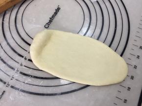 取一份面团，用擀面杖擀成椭圆形，顶部留少许不擀，尾部要擀薄