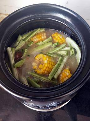 汤汁呈白色，玉米和腊肉的精华都熬了下来，尝一下豆角，熟了就可以尝味关火了。