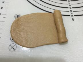 7. 取一个松弛好的面团，擀开边上气泡拍掉,翻面，自上往下卷起