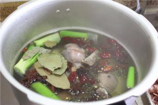 高压锅加水，加肘子，再放姜、花椒、干海椒、八角、三奈、草果、大葱、料酒、姜，加入老抽