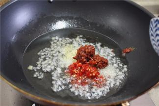 锅里入油，加入姜片、蒜、放豆瓣、泡椒炒香