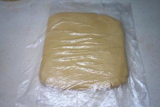 取一张保鲜膜，其实用一个保鲜袋剪开更好用噢；将面团放在保鲜膜中间，手按压平整，入冰箱冷藏保存至少30分钟后再用；