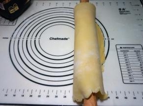 用擀面杖将面皮卷起来，这样面皮不会断裂；