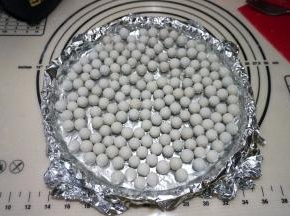 上铺锡纸，与面皮贴合，将烘焙石子撒在上面，如果没有烘焙石可以用干豆子或者锡纸包的石头放在上面代替；