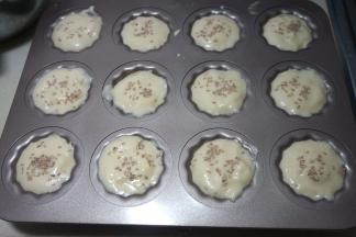 用小勺将鸡蛋糊舀入不粘烤模中，用纸模也是可以的，想要成品漂亮就8分满，这样涨起来之后就刚好露出一个小圆脑袋，我是想把所有蛋糊全放进去，装得有些满了，但最后还是用了两个纸杯模；表面撒点白芝麻