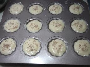 用小勺将鸡蛋糊舀入不粘烤模中，用纸模也是可以的，想要成品漂亮就8分满，这样涨起来之后就刚好露出一个小圆脑袋，我是想把所有蛋糊全放进去，装得有些满了，但最后还是用了两个纸杯模；表面撒点白芝麻