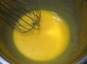 蛋黄中加入40克玉米油，用手动打蛋器混合均匀