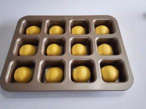 面团用手掌按扁排气，然后包入椰蓉内馅，收口朝下摆放到模具里面。