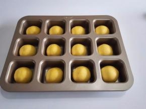 面团用手掌按扁排气，然后包入椰蓉内馅，收口朝下摆放到模具里面。