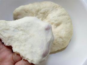 这是静置过的面团，已经可以拉出一层稍厚不易破的膜。
 这时再用厨师机、面包机或手去揉就都能把面团揉到位的，.我们需要尽力的揉到能拉出稍微薄一些且结实的膜。因为在将面团滚圆的时候，如果没有揉出膜，面团表面就会是不光滑的，在后面贝果面团整形时，表面也就不能光滑，不仅会使成品有褶皱影响美观，也会影响发酵。所以虽然不用揉到完全阶段，也尽力揉到扩展阶段吧， 至少要使面团表面光滑。