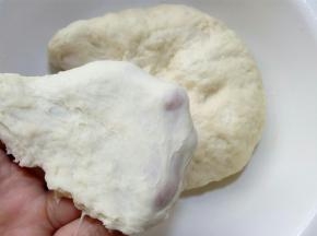这是静置过的面团，已经可以拉出一层稍厚不易破的膜。
 这时再用厨师机、面包机或手去揉就都能把面团揉到位的，.我们需要尽力的揉到能拉出稍微薄一些且结实的膜。因为在将面团滚圆的时候，如果没有揉出膜，面团表面就会是不光滑的，在后面贝果面团整形时，表面也就不能光滑，不仅会使成品有褶皱影响美观，也会影响发酵。所以虽然不用揉到完全阶段，也尽力揉到扩展阶段吧， 至少要使面团表面光滑。