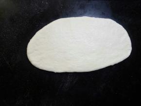 松弛好的面团擀成椭圆形，用手尽力拍掉气泡。擀面的时候不要太用力，光滑的一面在上面，这样整形好的贝果表皮才不会裂开。 这时如果面团擀不开，就需要再松弛一会儿。尽量不要去硬擀开。
 
