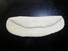 将其翻面，与身体平行的横放在操作台上 ，自三分之一处内折，用手掌根部拍紧，防止有空气。