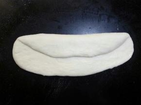 将其翻面，与身体平行的横放在操作台上 ，自三分之一处内折，用手掌根部拍紧，防止有空气。