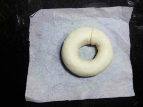 剪五张比圆环稍大的油纸(因为等下煮的时候方便拿取，不会粘在烤盘上，而破坏了整好的形状。)把整型好的面团放在油纸上，再整理一下圆环的形状，保证中间孔洞不要太小。
 