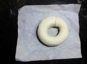 剪五张比圆环稍大的油纸(因为等下煮的时候方便拿取，不会粘在烤盘上，而破坏了整好的形状。)把整型好的面团放在油纸上，再整理一下圆环的形状，保证中间孔洞不要太小。
 