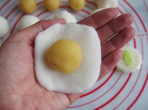 将饼皮压扁，放入绿豆沙馅，用虎口收紧。