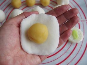 将饼皮压扁，放入绿豆沙馅，用虎口收紧。