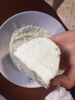 盘子里放着奶粉，涂满乳酪馅的那面沾满奶粉即可