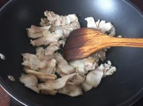 五花肉用开水煮熟后切成薄片，放入锅中煸出油，煸至表面金黄即