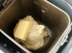 除了黄油之外的披萨面团材料，放入面包机。开启饺子面团程序。运行到一半时间，剩余七分钟的时候，打开盖子。看到光滑的面团，放入室温软化的黄油，继续运行到程序结束。