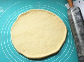 发酵好的面团，排出其中的大气泡，静置一小会后团擀成薄片，比披萨盘略大。