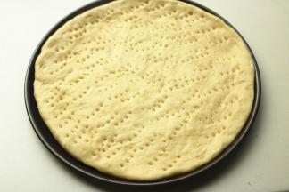 面胚放入披萨盘，整理一下边缘，用叉子叉出小孔，避免烤的时候鼓泡。