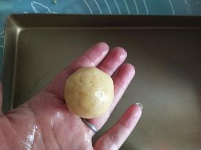 手心里摸少量的熟玉米油，取大概30克左右的绿豆泥，搓圆球