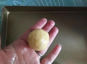 手心里摸少量的熟玉米油，取大概30克左右的绿豆泥，搓圆球