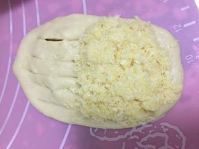 用擀面杖将松弛好的面团擀成长舌状，一端用剪刀剪开，不要剪断，然后在一端勺入椰蓉