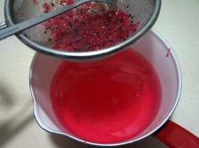 将火龙果果酱放在筛网中，再浸入糖水中，用小勺轻轻搅拌，使大果肉和籽留在筛网上，弃之不用