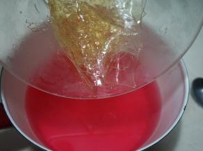 将火龙果糖水液重新坐在火上，煮开后，将泡软的吉利丁片放入其中，搅拌至融化
